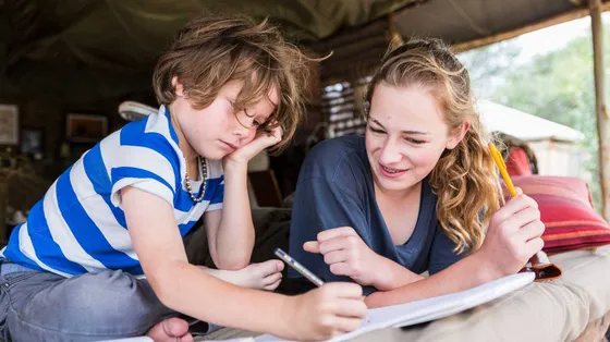 Fratello e sorella fanno i compiti della vacanze in tenda in Francia