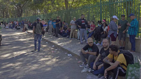 Gruppi di rifugiati in attesa seduti su n marciapiede di Città del Messico