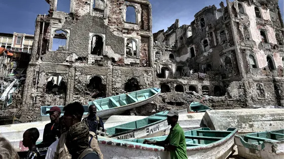 Barchette dei pescatori bianche e azzurre. Sullo sfondo, rovine degli edifici