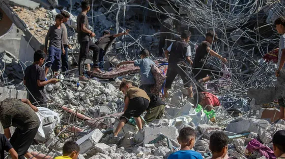 Una decina di persone, tra cui almeno 6 bambini, si muovono sulle macerie di un edificio crollato