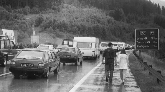 Una foto del 1996 scattata al confine tra Italia e Austria. Una coppia passeggia lungo la strada, bloccata da file interminabili di auto
