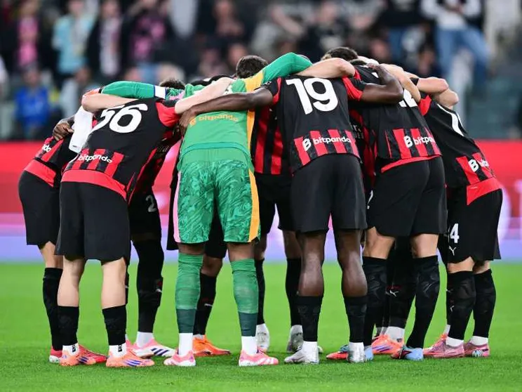 Giocatori del Milan in maglia rosonera radunati a centrocampo prima della partita