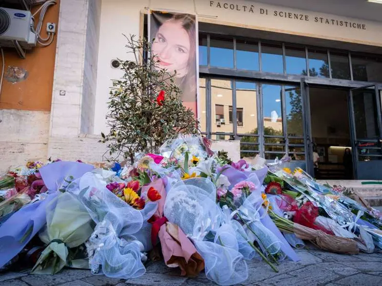 Nell'immagine sono visibili decine di mazzi di fiori lasciati davanti all'ingresso della Facoltà di Scienze della Sapienza di Roma per ricordare le donne vittime di femminicidio