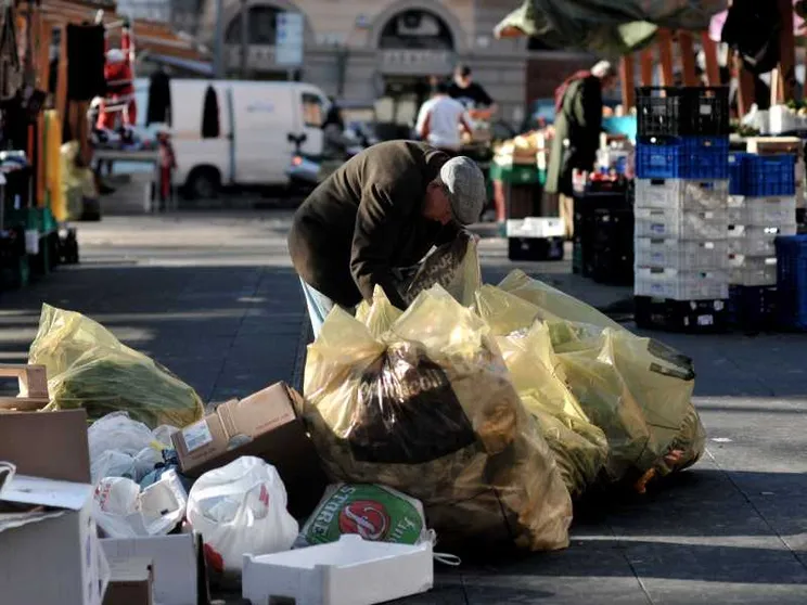 Un anziano fruga tra i rifiuti del mercato di piazza S. Cosimato a Trastevere, a Roma per cercare del cibo da mangiare