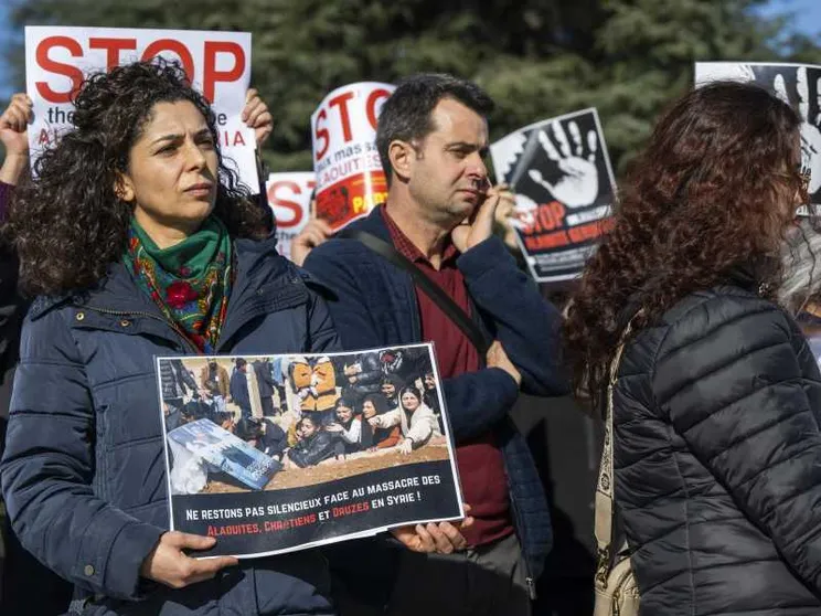Una donna con un cartello che recita: "Non restiamo in silenzio davanti al massacro di alauiti, cristiani e drusi in Siria"