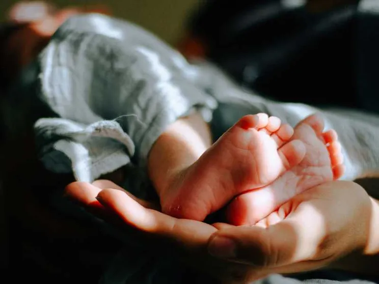 Una mamma tiene tra le mani i piedi del suo bambino. Foto d'archivio