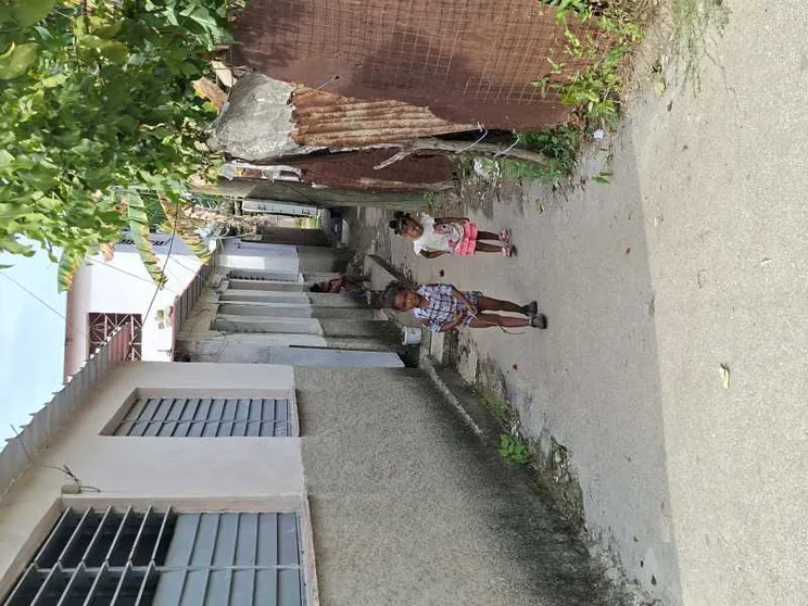 Due bambini cammino in un viottolo sterrato di una baraccopoli dell'Avana su cui si affacciano casupole di compensato e lamiera