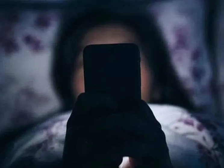 Una ragazzina davanti al suo smartphone in cameretta