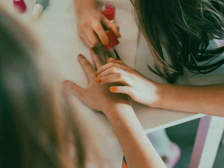 Una bimba gioca a fare lo smalto a una sua amichetta