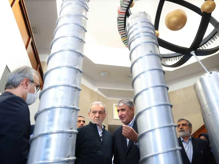 Un gruppo di funzionari iraniani e il presidente Massud Pezeshkian ispezionano dei grandi cilindri grigi in uno degli impianti del programma nucleare