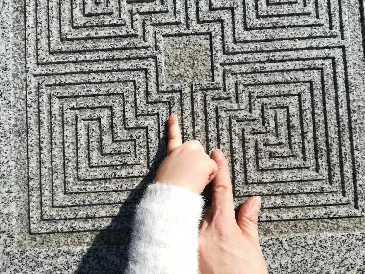 Due dita si muovono su un labirinto di pietra