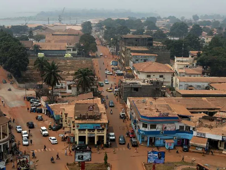 Una strada in terra battuta attraversa la capitale della Repubblica Centrafricana, Bangui. Gli edifici appaiono come fatiscenti. Il colore dominante è l'arancione.