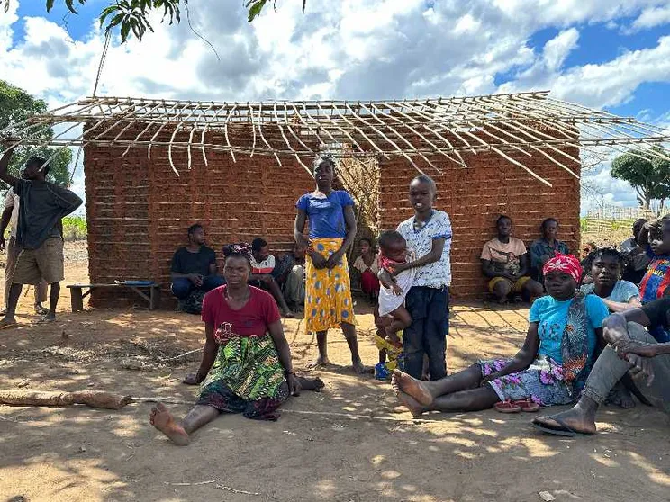 Donne e uomini seduti davanti a una capanna tradizionale di canne nel villaggio di Nannona, nella provincia mozambicana di Cabo Delgado