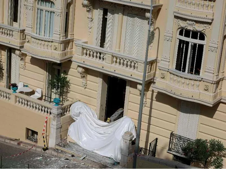 L'ingresso di un edificio è coperto al piano terra da un telo bianco. Al primo piano, un terrazzo.