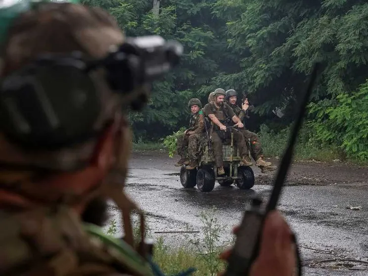 Quattro militari su un mezzo. In primo piano, sfocato, un militare di spalle che parla a un radio trasmettitore