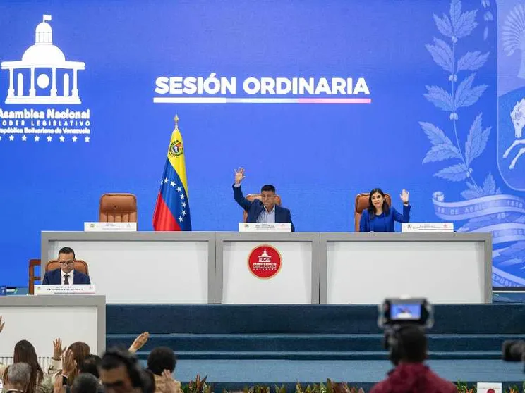 Un lungo tavolo bianco con la bandiera venezuelana e due persone sedute