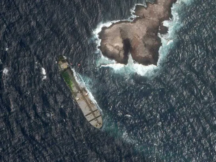 Dal satellite, l'immagine di una nave in mare poco distante da una penisola. Sulla nave è visibile una zona verde: sono alghe