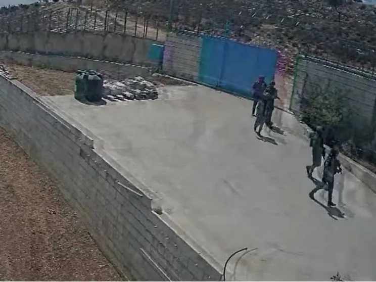 Soldati che fanno irruzione dentro a un cancello. Visti da lontano