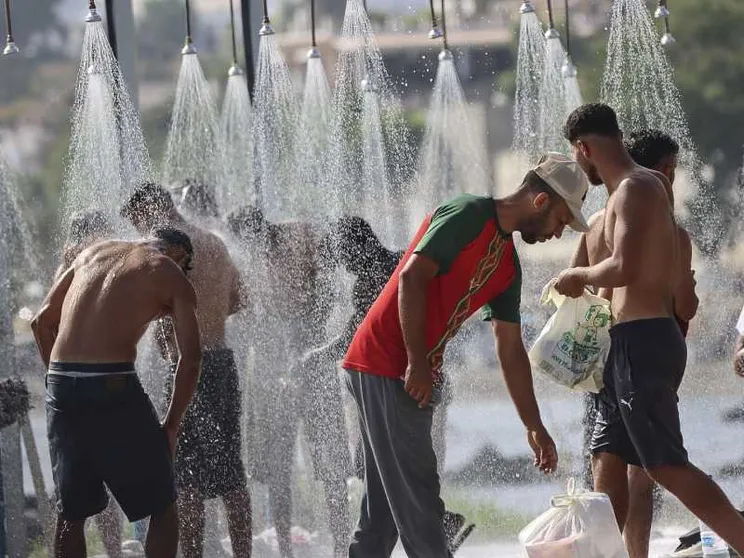 Alcuni migranti fanno la doccia sulla spiaggia di Trampolin a Ceuta