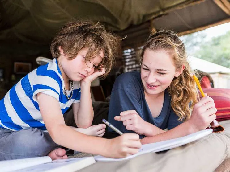 Fratello e sorella fanno i compiti della vacanze in tenda in Francia