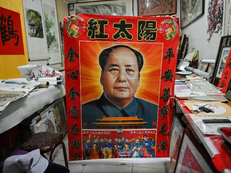 Un venditore ambulante mostra un poster di Mao Zedong a Pechino