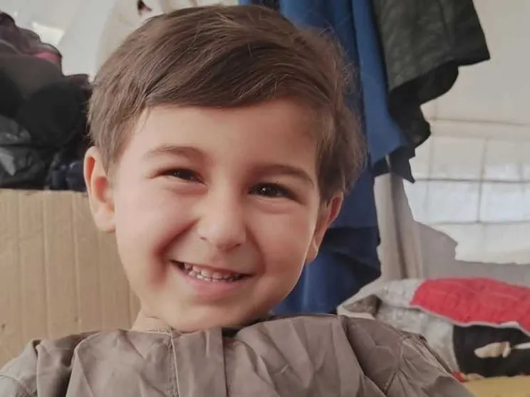 Il volto sorridente di un bambino dai capelli castani