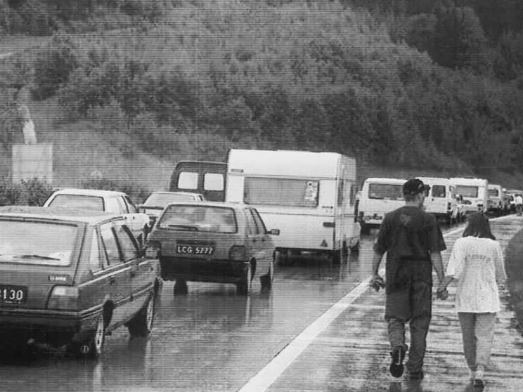 Una foto del 1996 scattata al confine tra Italia e Austria. Una coppia passeggia lungo la strada, bloccata da file interminabili di auto