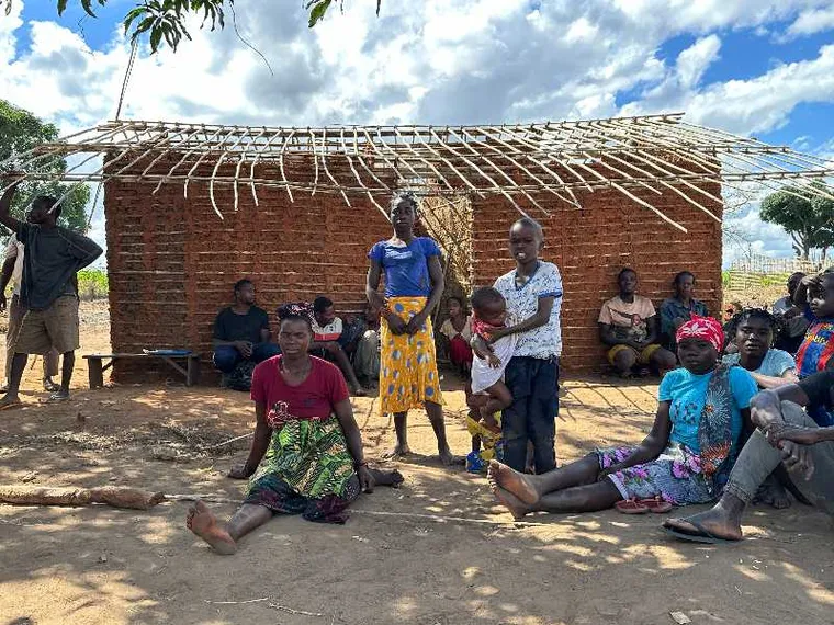 Donne e uomini seduti davanti a una capanna tradizionale di canne nel villaggio di Nannona, nella provincia mozambicana di Cabo Delgado