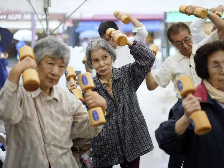 Anziani praticano attività fisica con manubri di legno durante un evento per la "Giornata di rispetto per gli anziani" a Tokyo