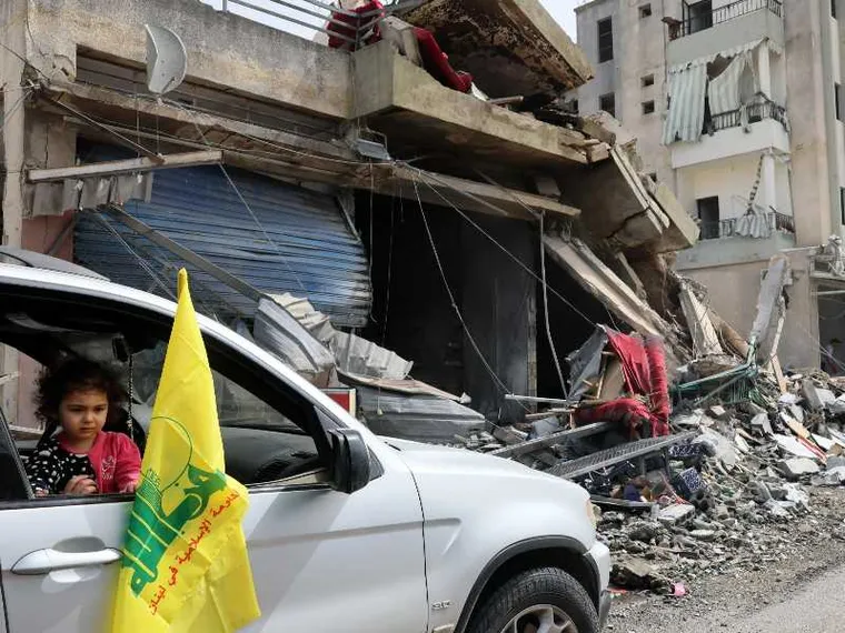 Un’auto con la bandiera gialla di Hezbollah si sposta fra le macerie di Nabatieh, nel Libano meridionale/ ANSA