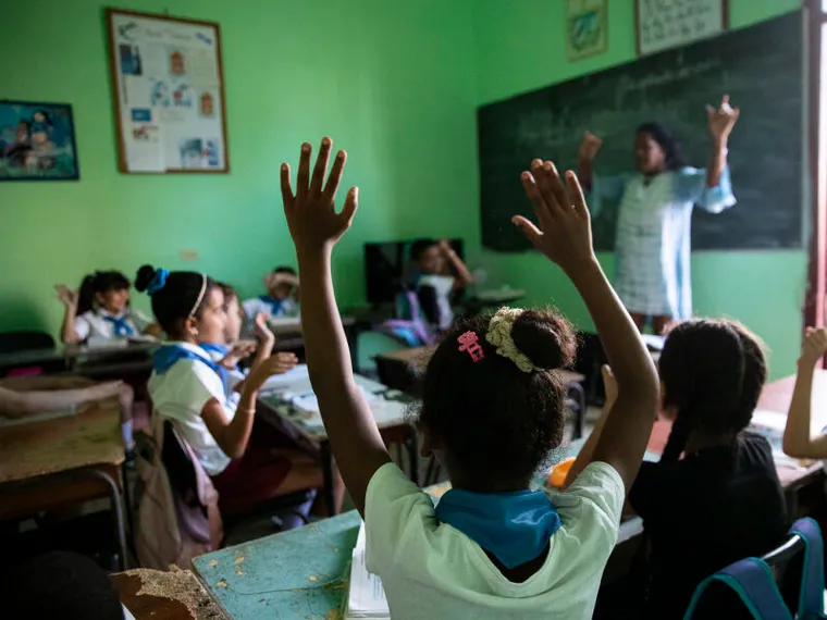 Bambini alzano le mani in classe