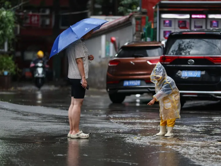 Mamma e figlia in strada sotto la pioggia
