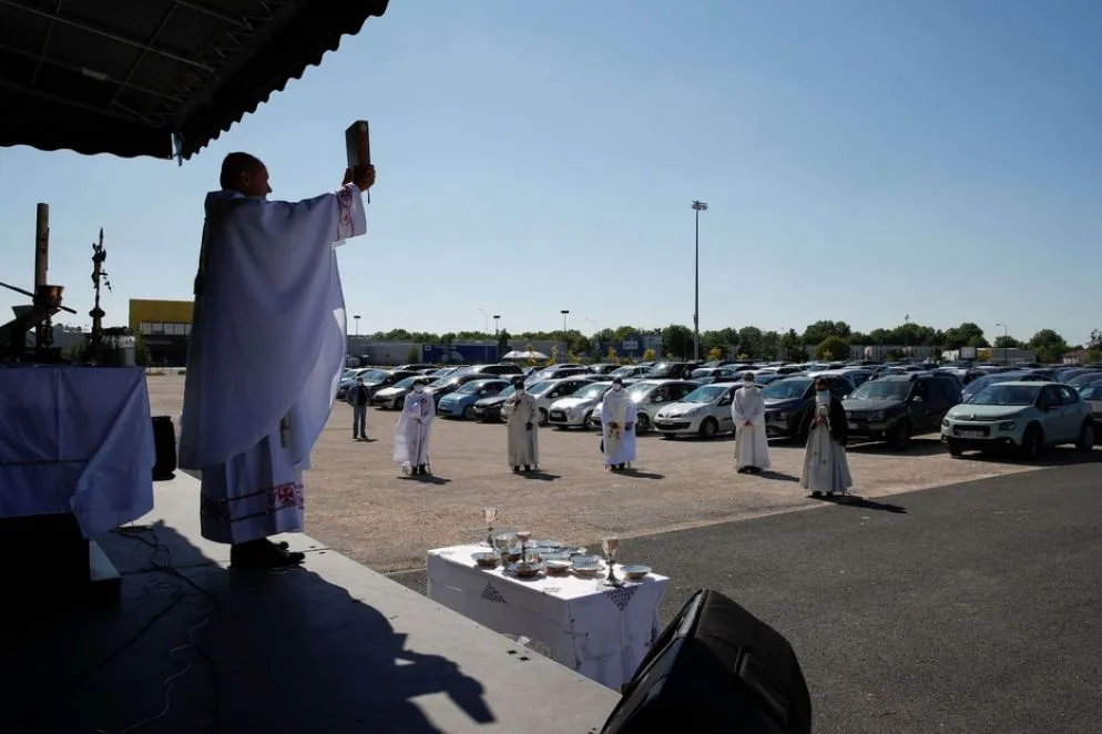 I sacerdoti hanno percorso tutte le file di auto parcheggiate per distribuire l'eucaristia, rigorosamente consegnata nelle mani dopo un passaggio con il disinfettante idroalcolico