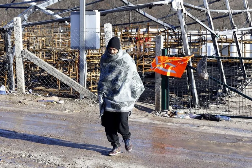 Un uomo davanti a quel che resta del campo di Lipa, bruciato nell'incendio del 23 dicembre