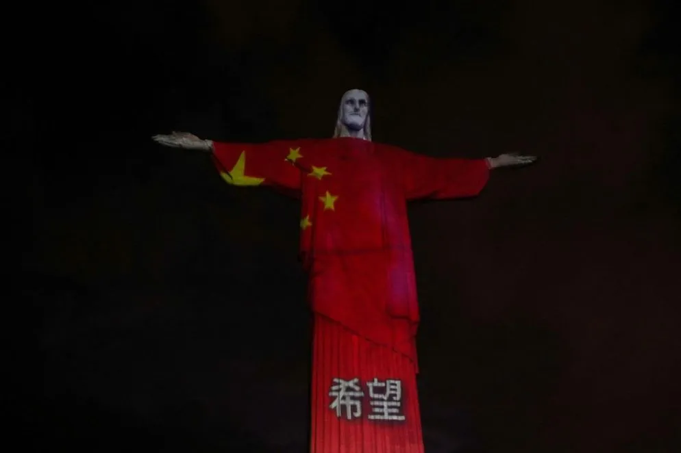 Le luci proiettano sulla statua la bandiera della Cina, il primo Paese a fare i conti con la pandemia