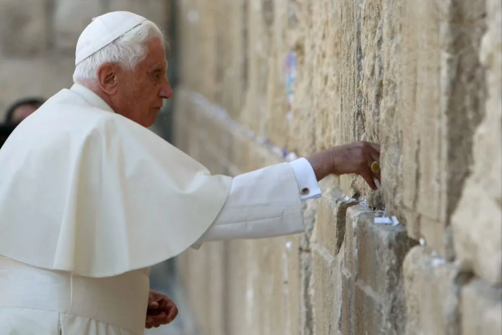 Il legame con la città di Gerusalemme. Vi tornerà anche da Papa nel 2009 con un viaggio apostolico che tocca Giordania, Israele e Territori palestinesi. Un tornare nei luoghi di Gesù, figura alla quale Ratzinger dedicherà ben tre libri: “L’infanzia di Gesù”, “Gesù di Nazaret. Dal Battesimo alla Trasfigurazione” e “Gesù di Nazaret. Dall’ingresso a Gerusalemme alla Risurrezione”. Un’opera, che Ratzinger completò durante il suo pontificato, ma non volle attribuirle il valore di un testo papale, bensì quello di uno studioso teologo, come Ratzinger, in fondo, ha sempre voluto essere. Del resto dopo la sua ordinazione sacerdotale,  proseguì il suo cammino verso il dottorato e poi la cattedra di teologia all’Università di Stato in Germania. Nella sua carriera universitaria insegnerà a Bonn, Munster, Tubinga, Ratisbona. Carriera che si interromperà nel 1977 quando Paolo VI lo nomina il 24 marzo nuovo arcivescovo di Monaco e Frisinga. Sceglierà come motto episcopale “ Collaboratori nella verità”. Viene creato cardinale il 27 giugno dello stesso anno da Paolo VI. Parteciperà ai due Conclavi del 1978 (agosto e ottobre), che elessero Giovanni Paolo I e Giovanni Paolo II. In quello del 2005 sarà eletto lui stesso Papa, con il nome di Benedetto XVI.