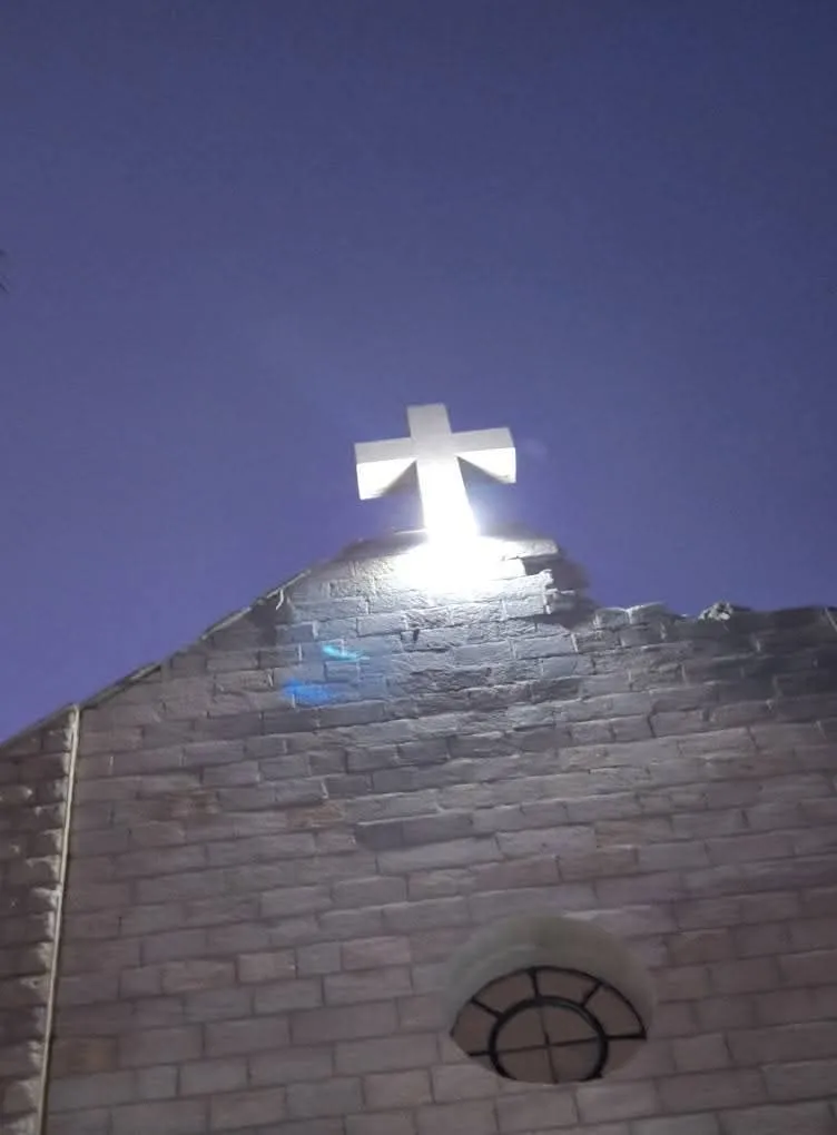 La croce illuminata sopra la chiesa della Sacra Famiglia a Gaza (dalla pagina Facebook di padre Gabriel Romanelli) 
