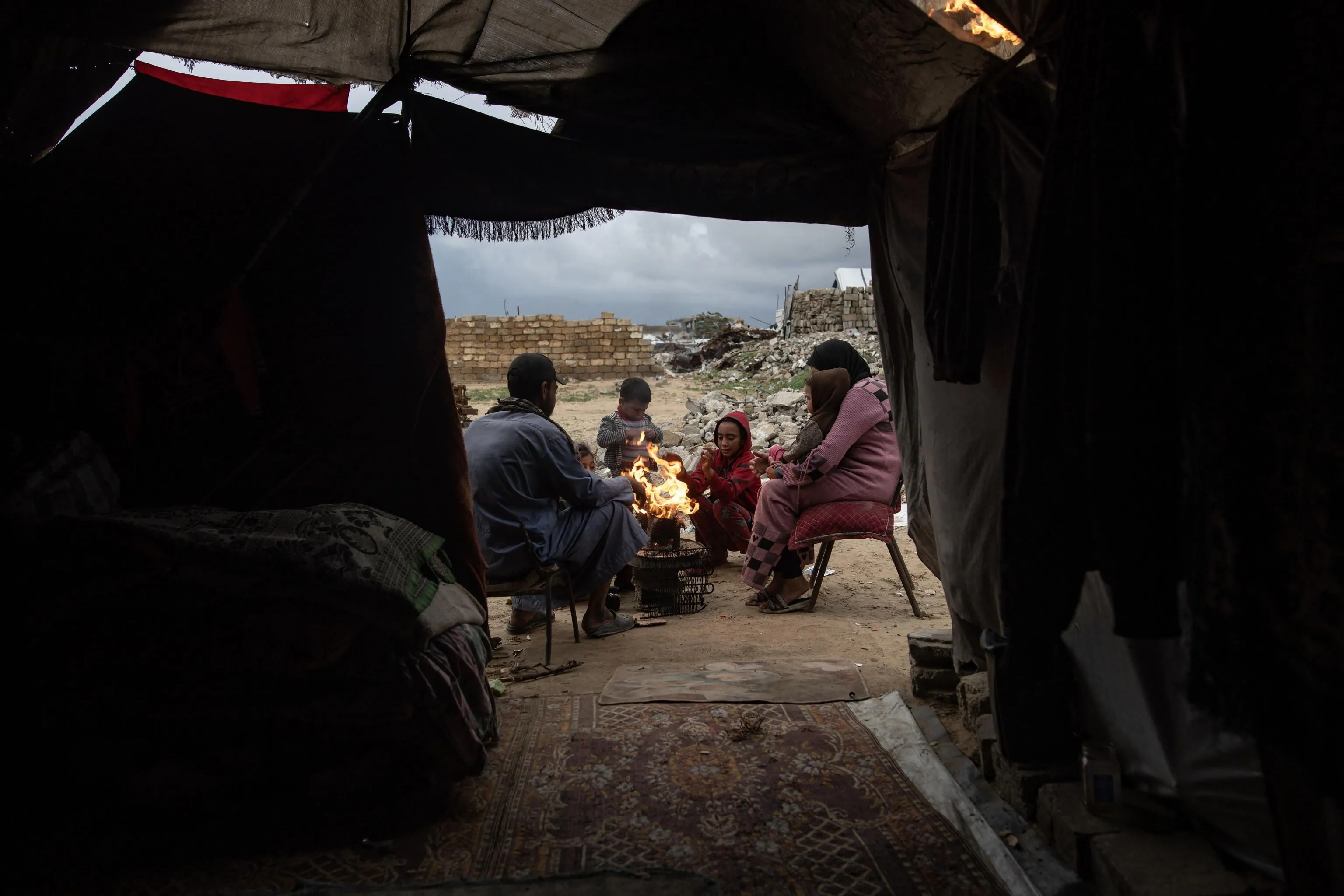 Una famiglia palestinese accende un fuoco per riscaldarsi fuori dal proprio rifugio nella città di Khan Yunis (sud di Gaza) /Ansa