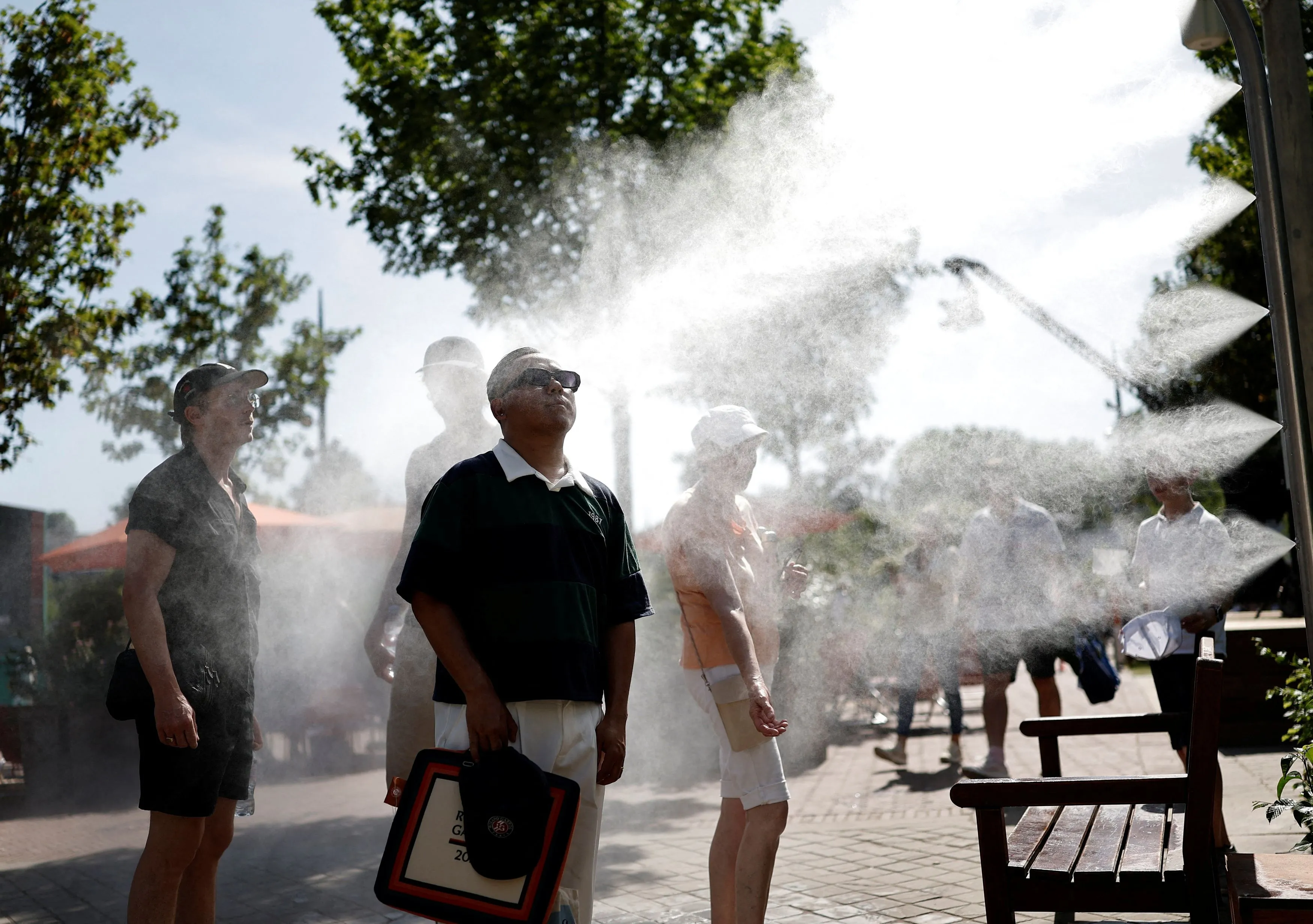Gli spettatori del Roland Garros a Parigi si rinfrescano presso una postazione con spruzzi d'acqua. (Foto di BENOIT TESSIER /REUTERS)