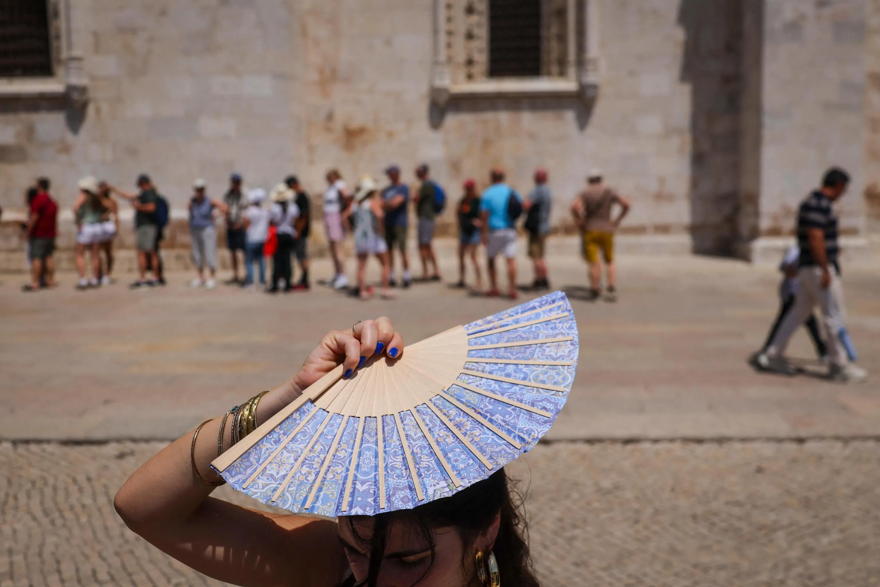 Una donna si ripara il viso con un ventaglio davanti al Monastero dos Jerónimos a Belém, in Portogallo (Foto di PATRICIA DE MELO MOREIRA / AFP)