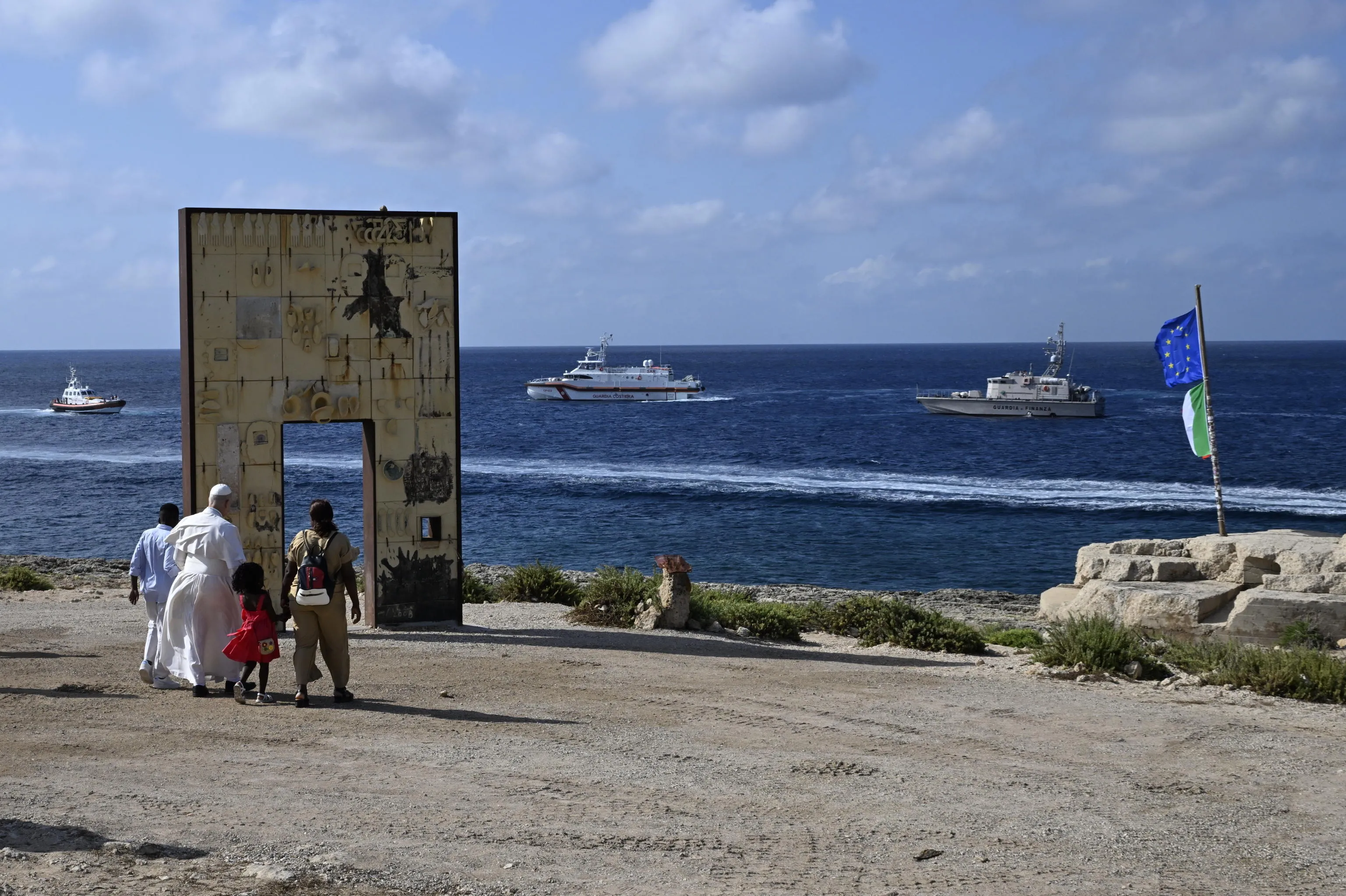 La visita di Papa Leone XIV a Lampedusa, il 4 luglio 2026. Prevost alla Porta d’Europa, il monumento che rende omaggio ai migranti ed è simbolo della frontiera più a sud dell’Italia e del continente; è accompagnato da una famiglie di migranti con i bambini / Ansa_Ciro Fusco