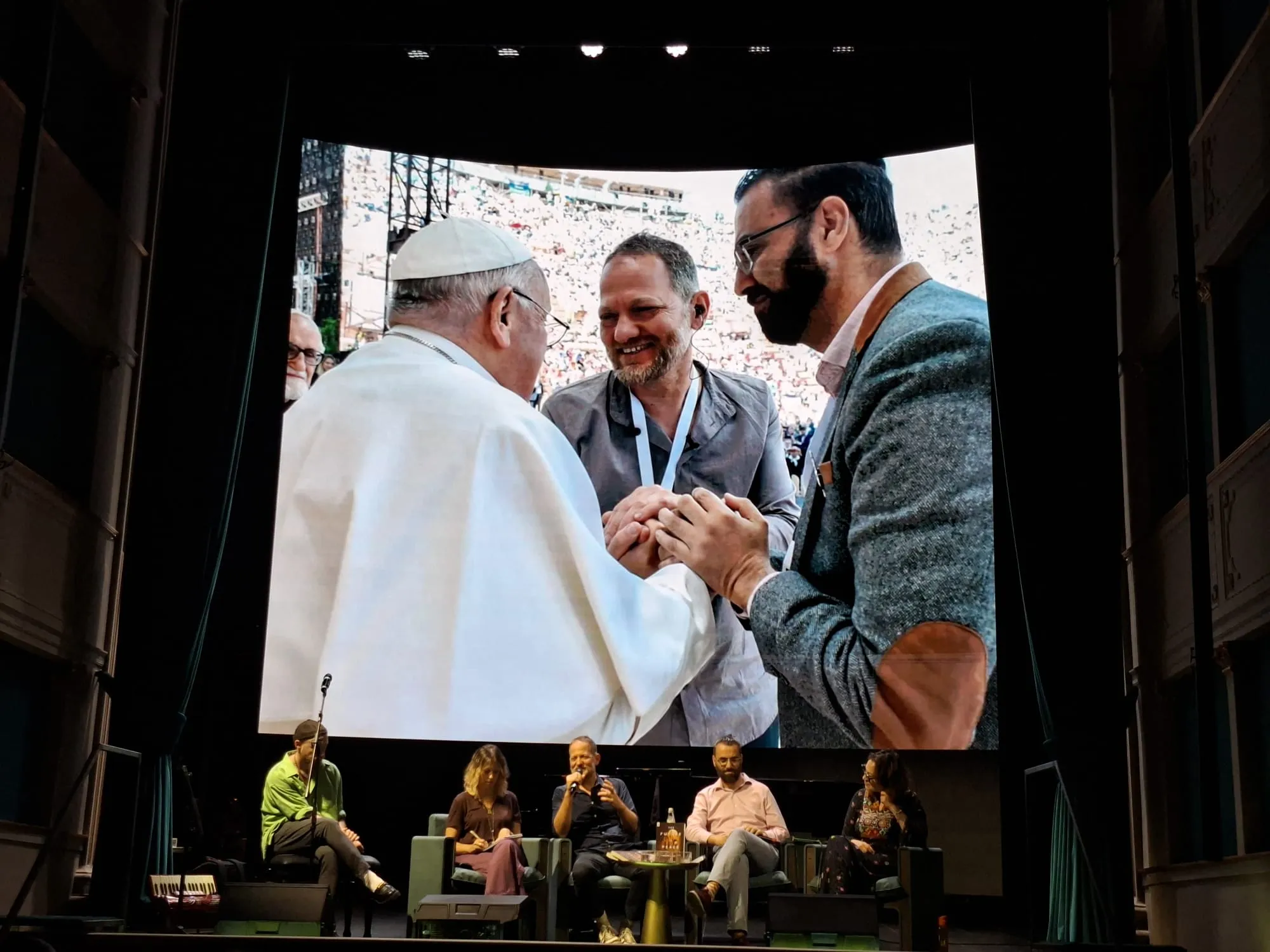Papa Francesco con Aziz Abu Sarah e Maoz Inon in una foto proiettata al teatro Nazionale. Un incontro reso possibile anche grazie al lavoro congiunto con "Avvenire". In basso, da destra Mira Awad, Aziz Abu Sarah, Maoz Inon e la traduttrice dell'incontro