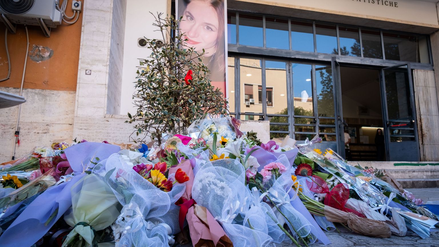 Nell'immagine sono visibili decine di mazzi di fiori lasciati davanti all'ingresso della Facoltà di Scienze della Sapienza di Roma per ricordare le donne vittime di femminicidio