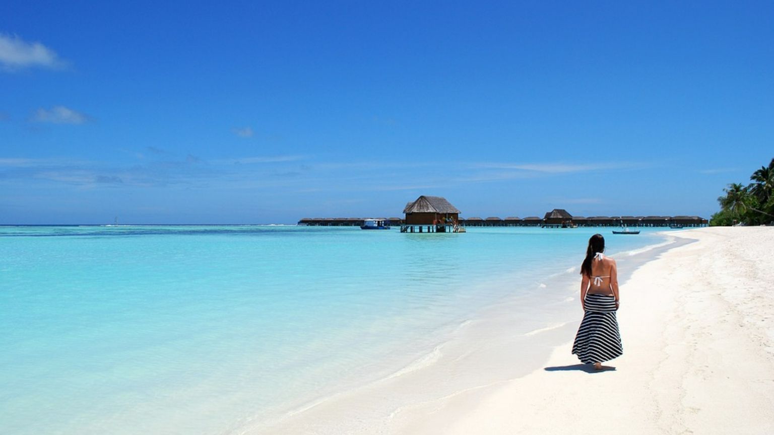 Una giovane cammina su una spiaggia delle Maldive