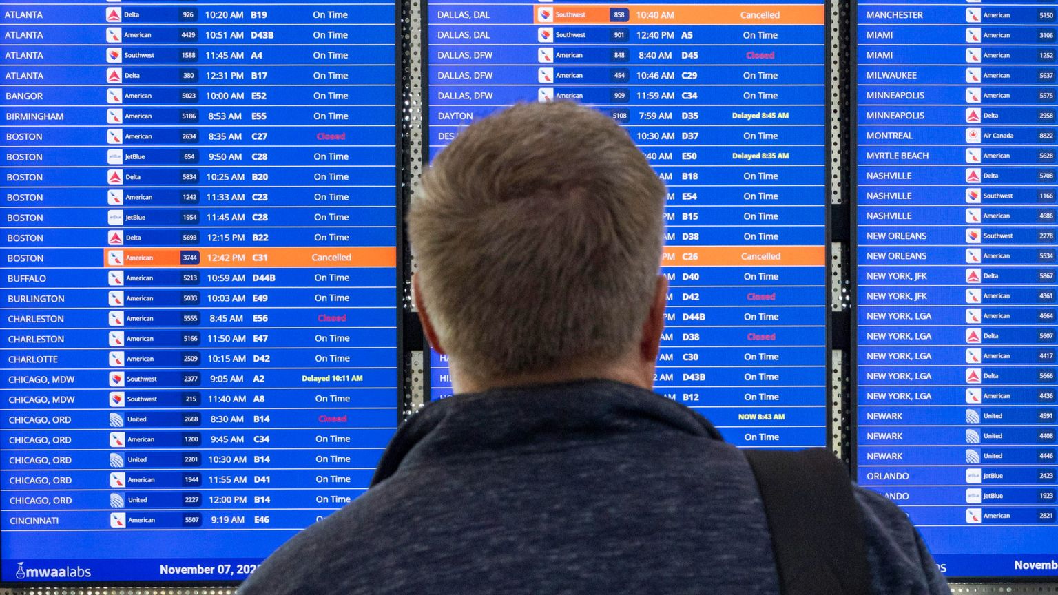 Un passeggero guarda il tabellone dove i voli Usa stanno ritornando regolari. Lo shutdown ha gettato nel caos il traffico aereo americano