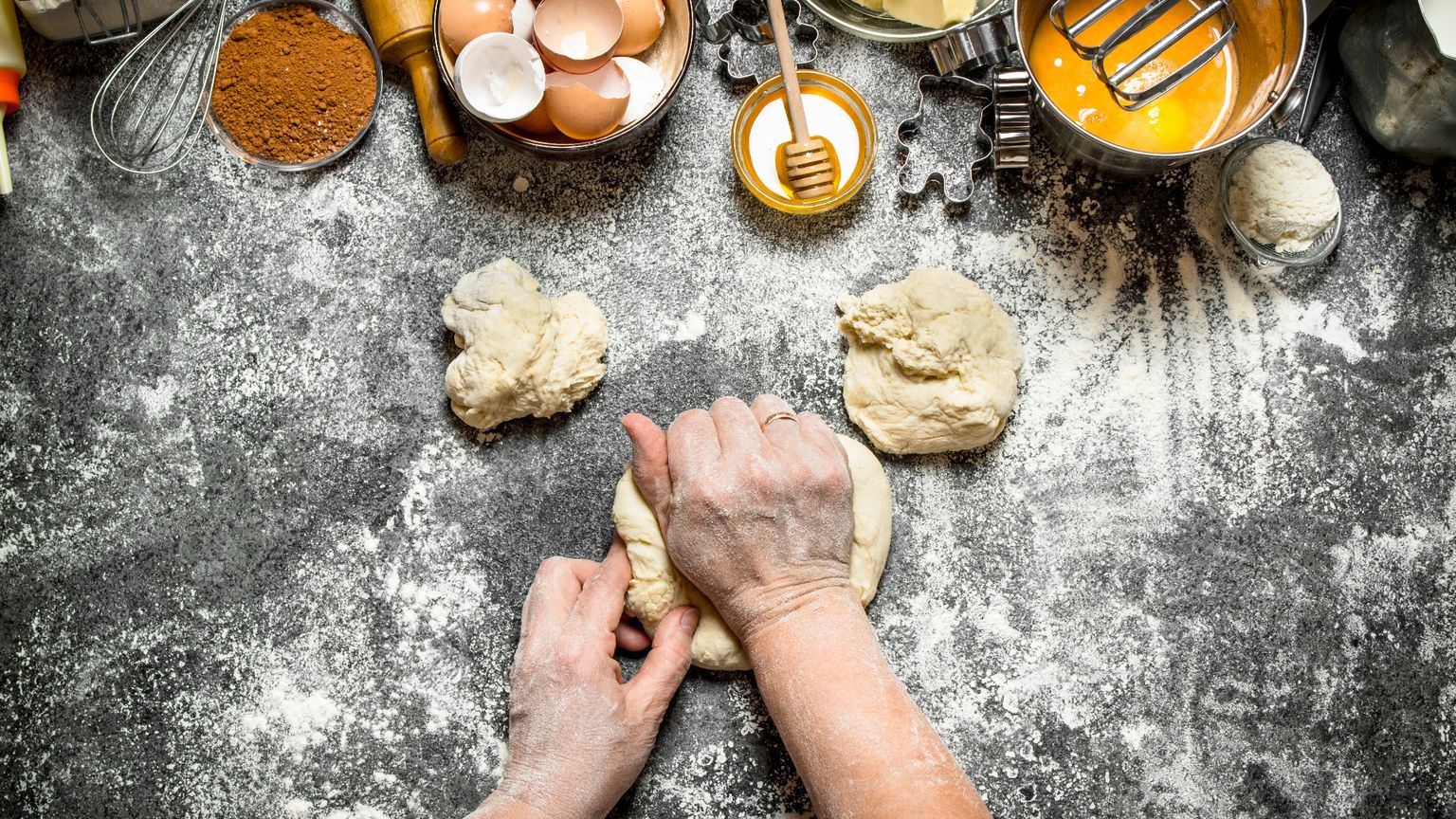 Mani che impastano su un tavolo con farina, uova