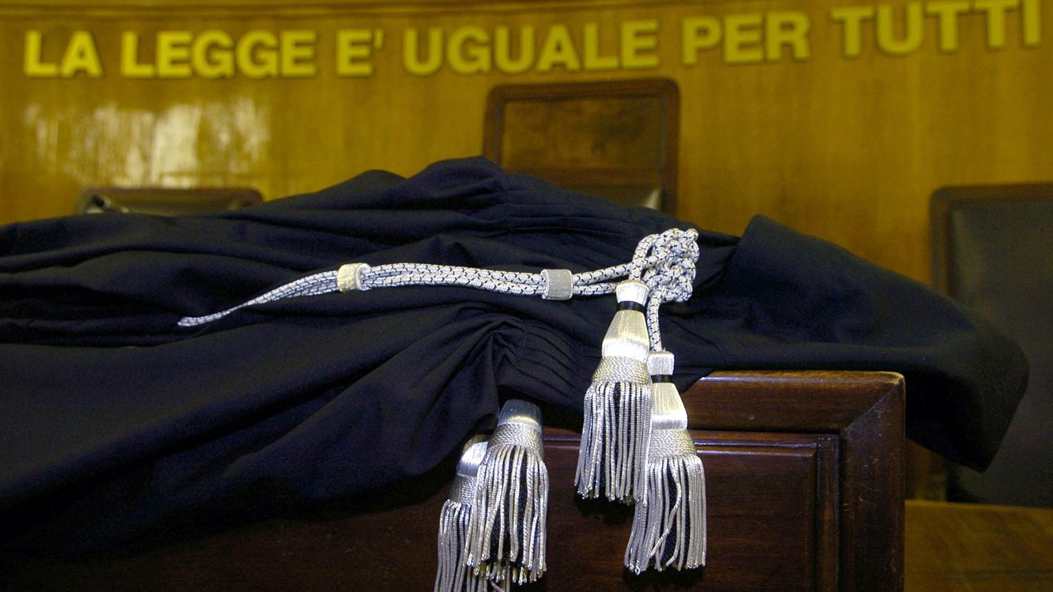 L'immagine ritrae una toga da magistrato sul banco di un Tribunale italiano, sullo sfondo la scritta "La legge è uguale per tutti"