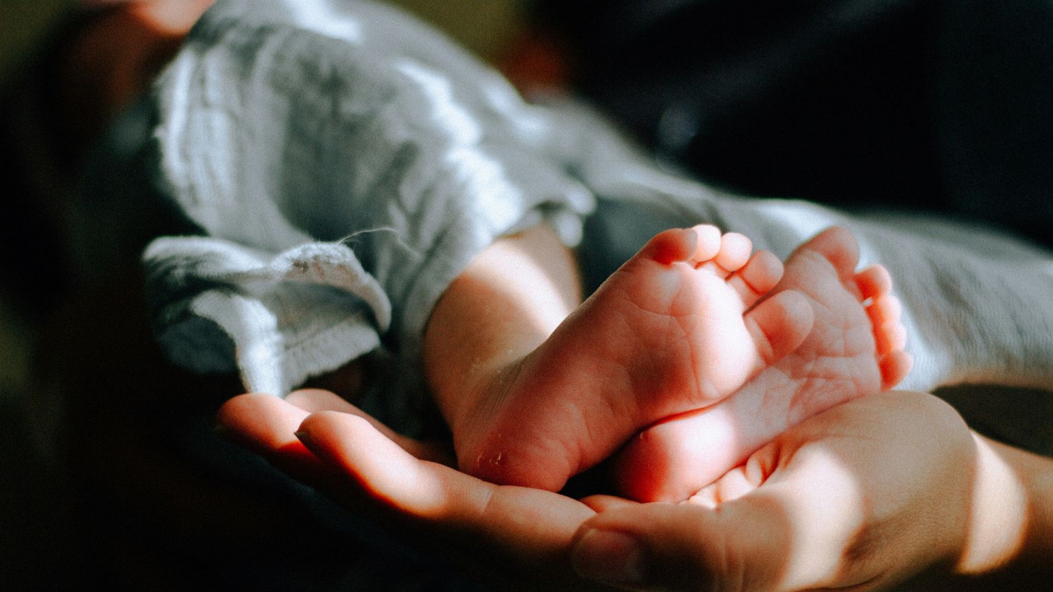 Una mamma tiene tra le mani i piedi del suo bambino. Foto d'archivio