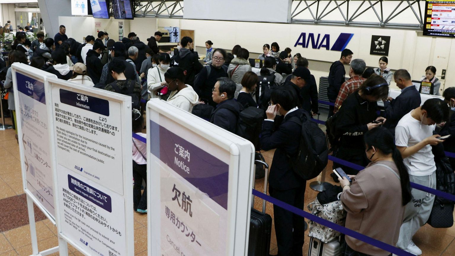 Passeggeri in fila all'Haneda Airport di Tokyo, dopo la cancellazione dei voli