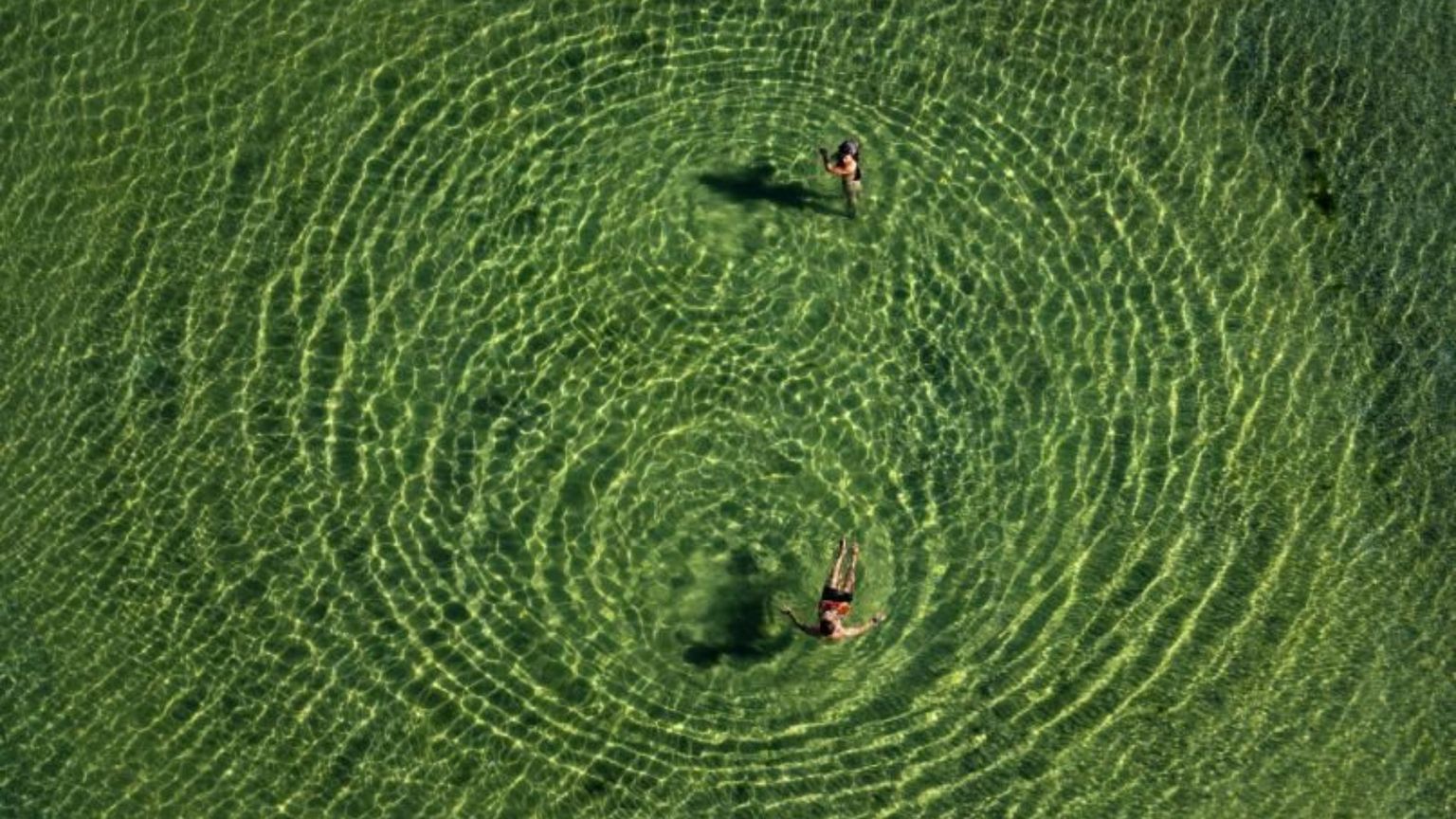 Due bagnanti in un lago del Trentino fra acque cristalline. Un'immagine sorprendente scattata da Massimo Sestini dall'elicottero